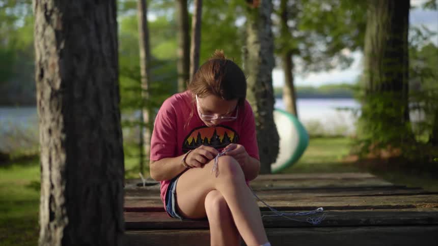 A girl is tying a knot by the lake