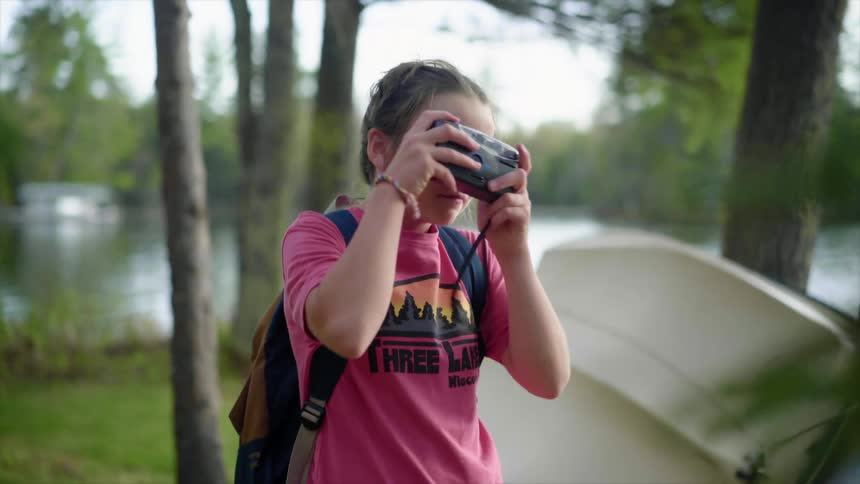 A girl takes pictures with a camera next to a lake
