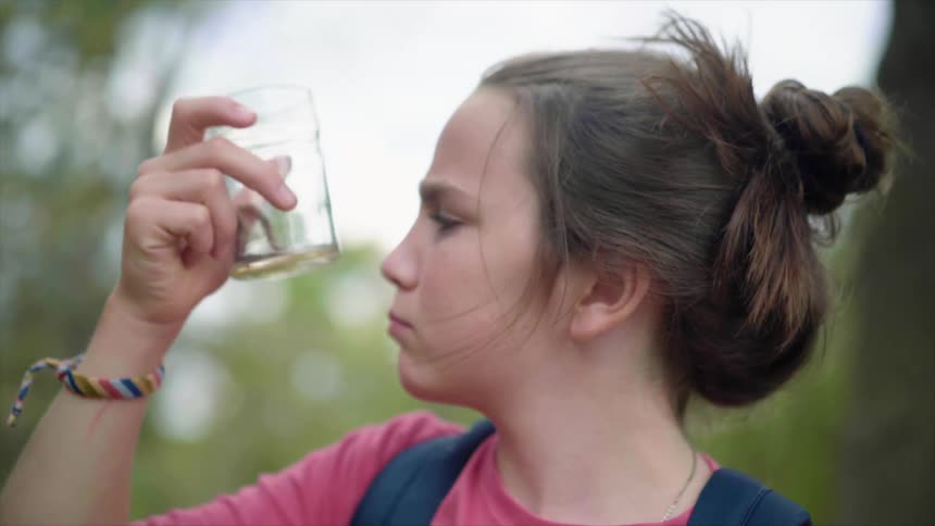 A young woman examines a worm in a glass jar