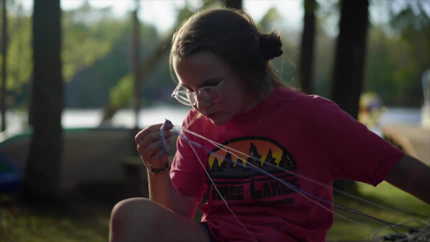 A young girl sits on the coast and works on a craft