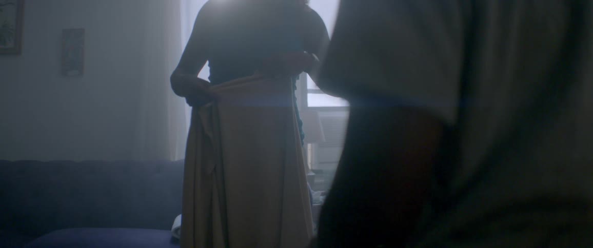 A woman and child fold a blanket indoors