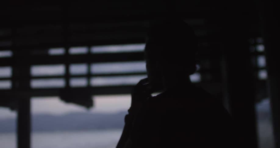 A man walks beneath a pier on a beach