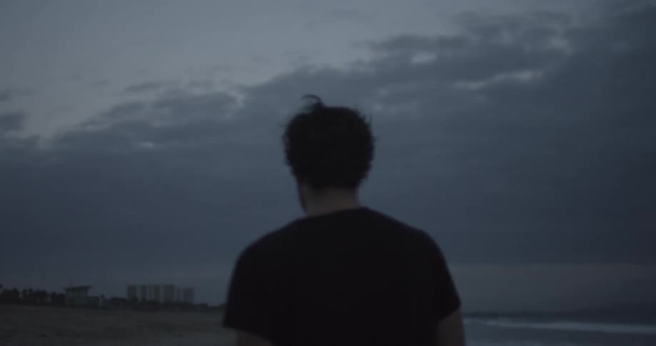 Man walking along a desolate beach on a cloudy day