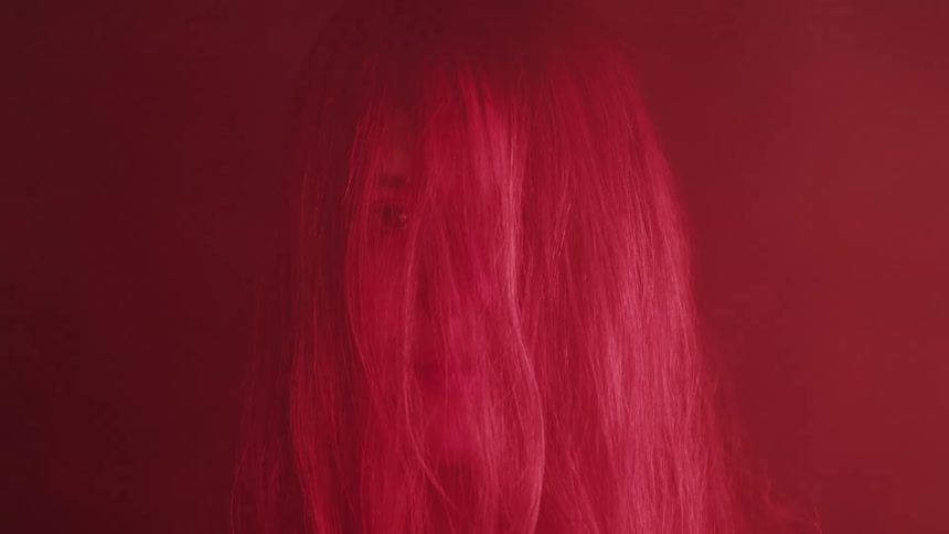 Light flickers on hair of woman standing in red tinted room