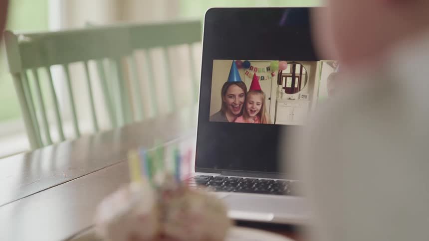 People celebrate a birthday with others over the computer camera