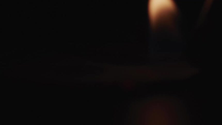 A fire from a torch being put on a hundred dollar bill on a table