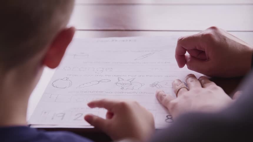 A woman helps a boy complete an educational worksheet