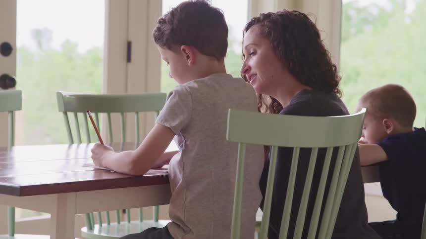 Mother with black curly hair helps her son study at home