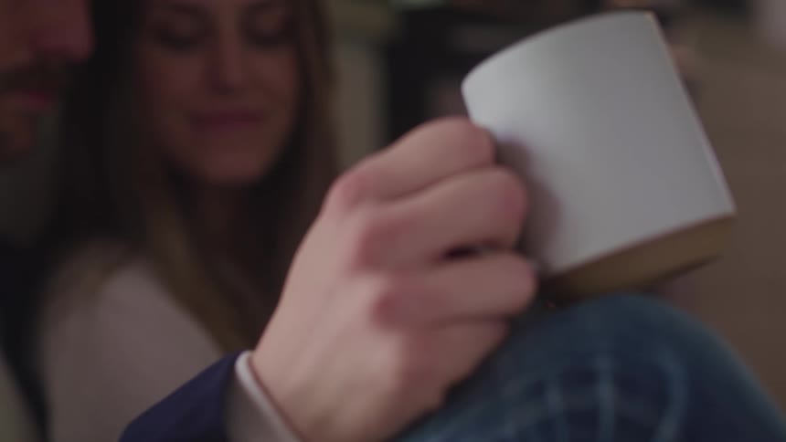 A man and woman tap their coffee mugs together and smile