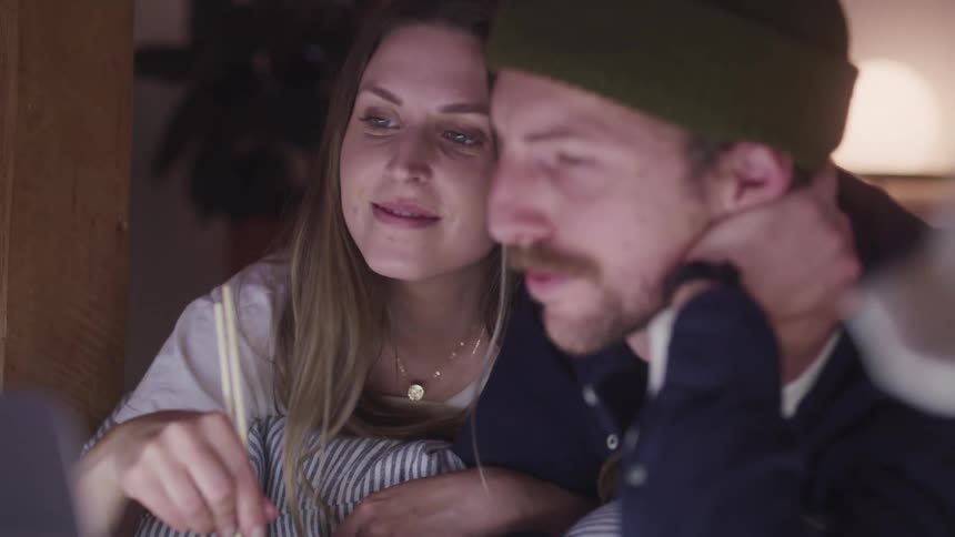 A man and woman smile and flirt while eating takeout