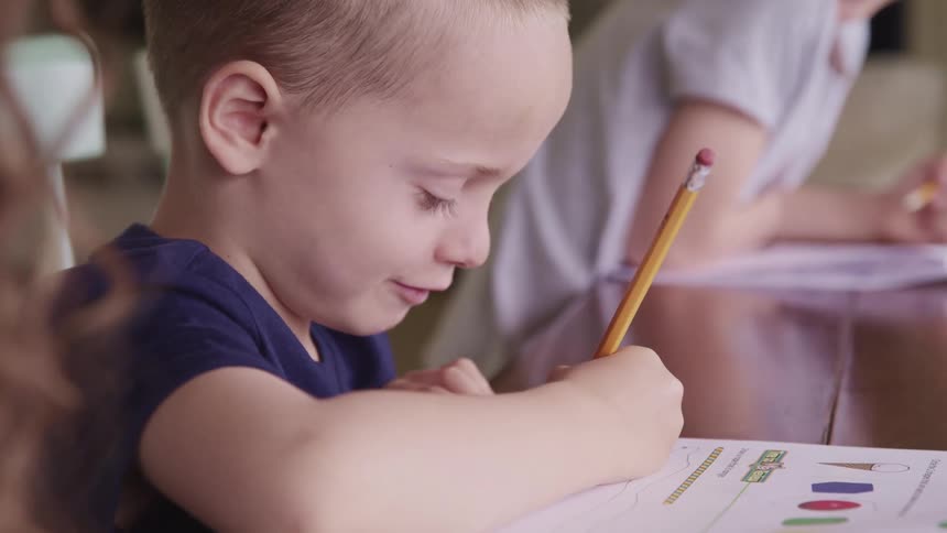 A mother watches her do school work at the table at home