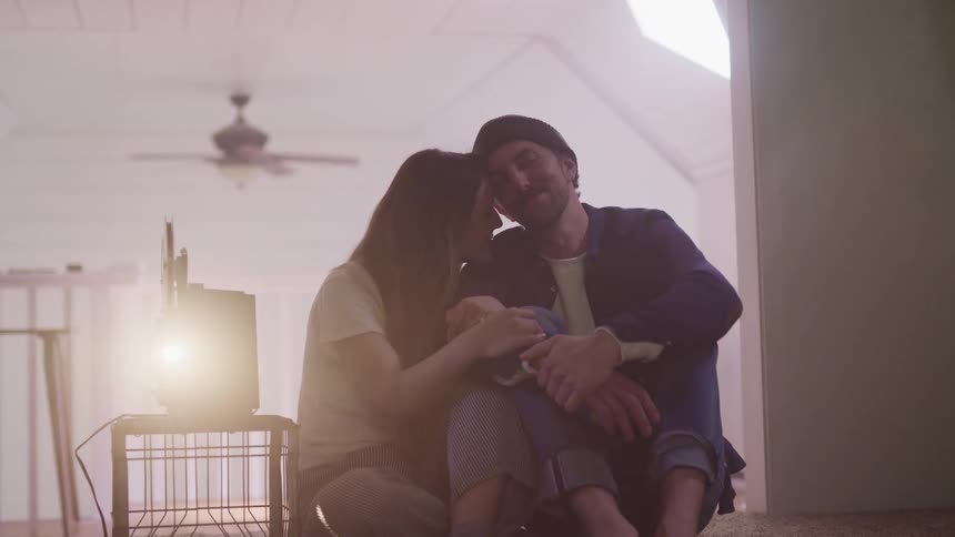 Man and woman hug as they watch a video from a projector