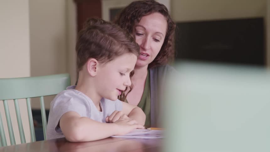 Mother with black curly hair helps son study at home