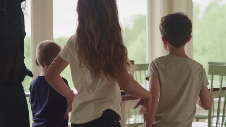 Children jumping and dancing in front of a table with a laptop