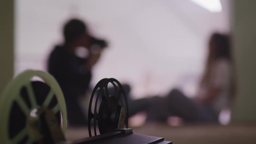 A person films a girl as she sits on the floor