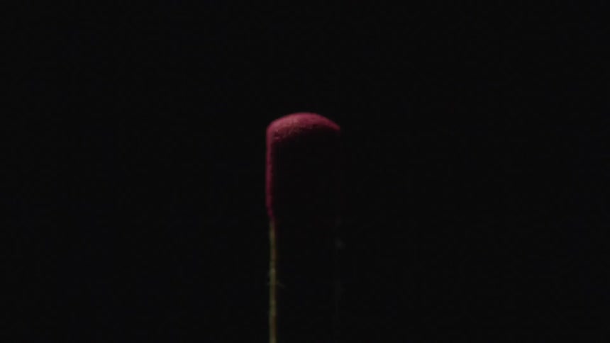 Close up of a match head dimly illuminated against a dark black background