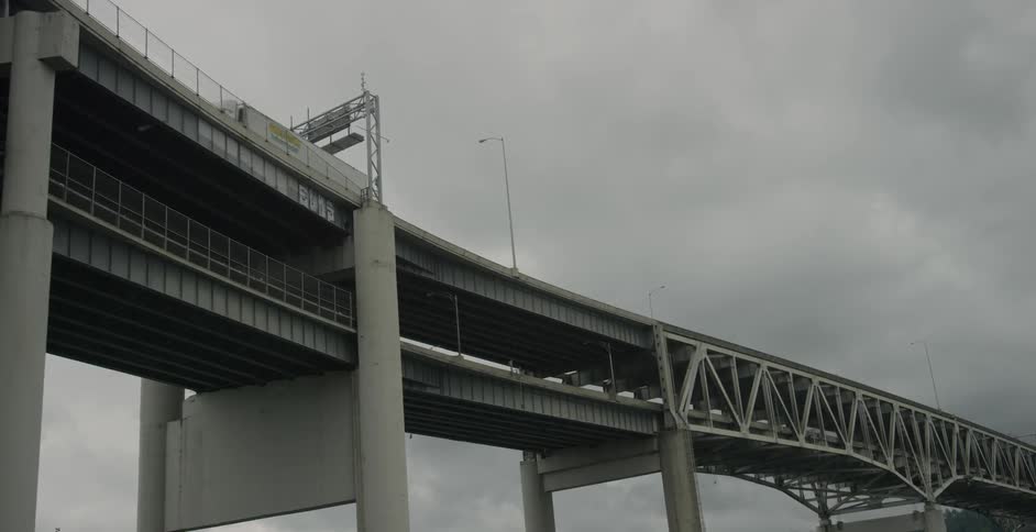 Vehicles are traveling over a bridge on a cloudy day