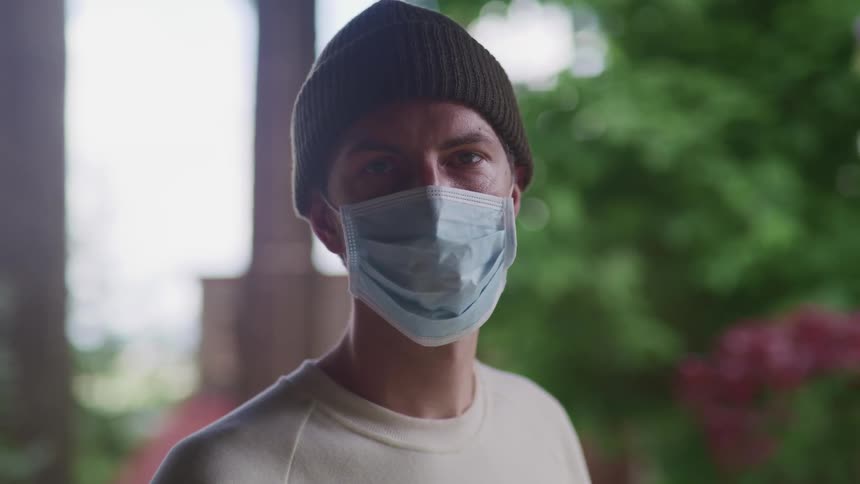 A man is standing outdoors while wearing a face mask