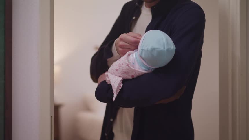 A father is holding his baby indoors