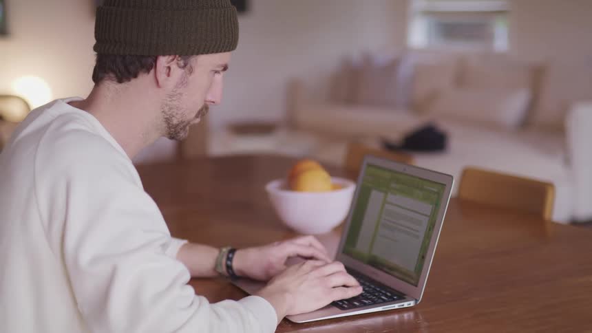 A man sits at home and works on his laptop