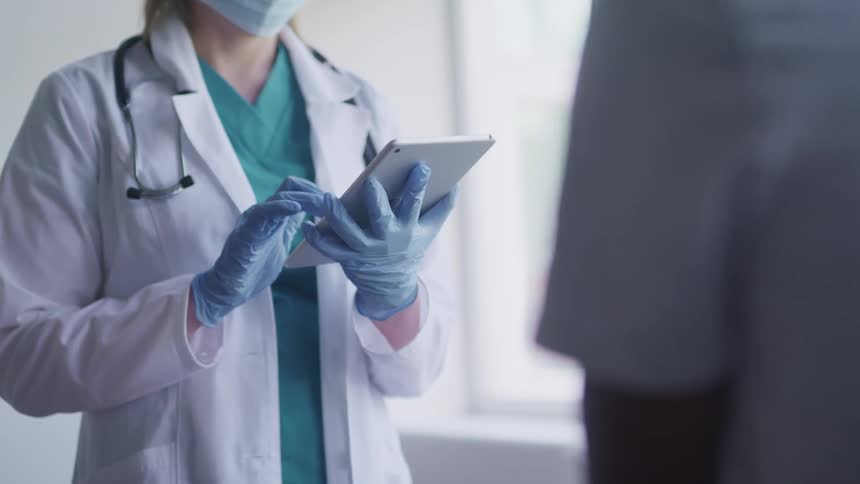 A doctor uses a tablet in front of a patient