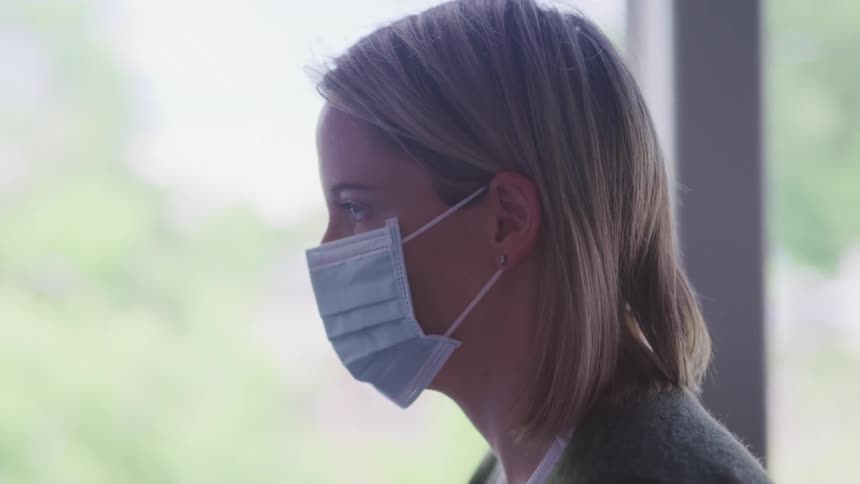 A woman is in an office building while wearing a mask