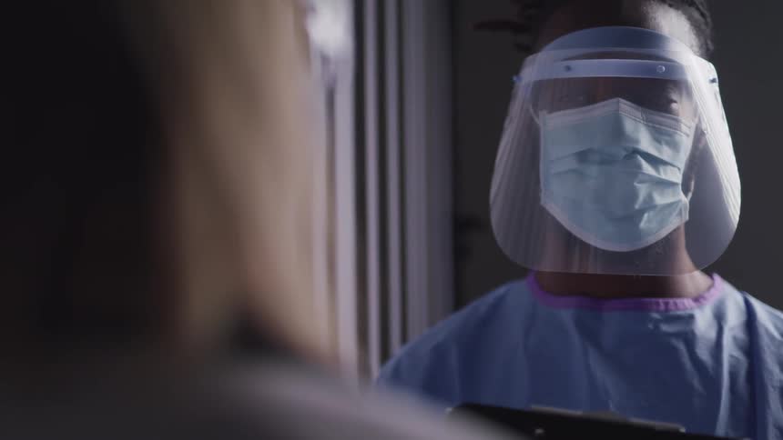 Two people stand together with face shields in the hospital