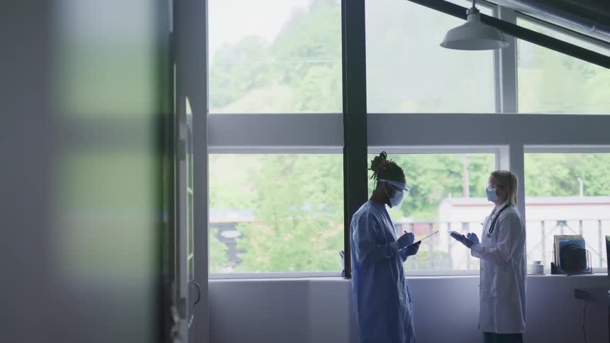 Two people in the hospital talk and use tablets