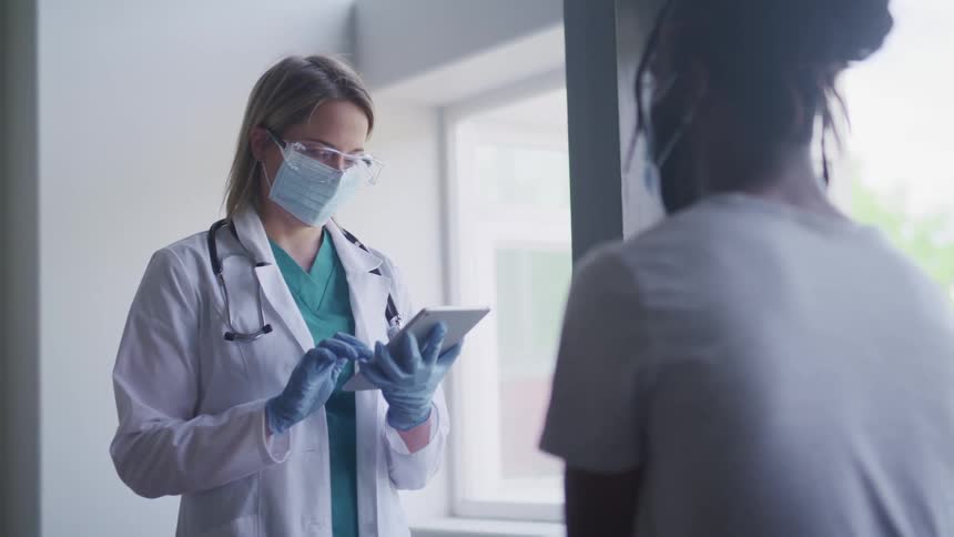 A nurse holds a tablet and talks with a patient