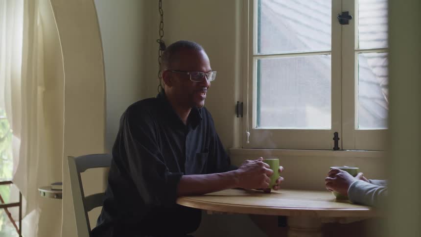 A man and woman are sitting at a table and drinking coffee