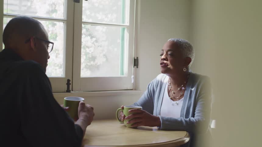 Elderly couple talks while enjoying a hot beverage at home