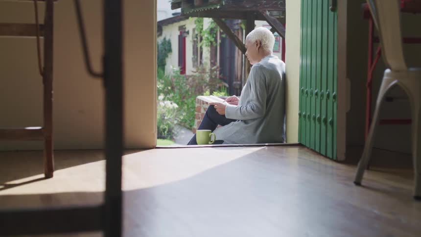 Woman relaxing with a book on steps of back porch
