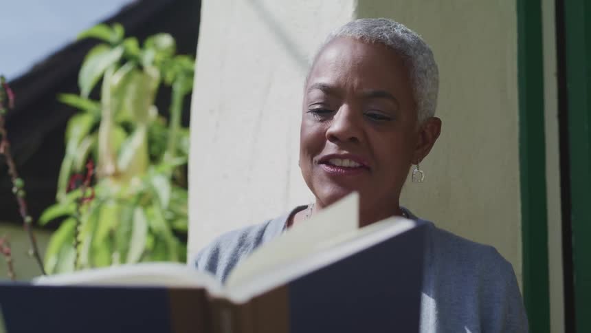 A woman is reading a book while sitting outdoors