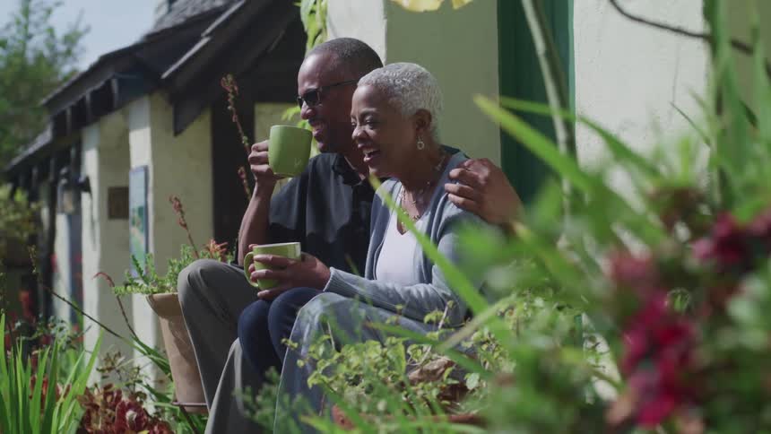 A man and woman are sitting outdoors in their backyard together