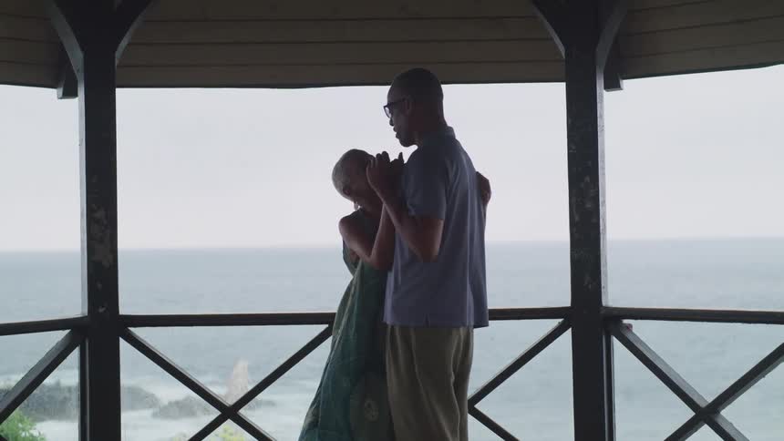 A man and woman are dancing outdoors next to the ocean