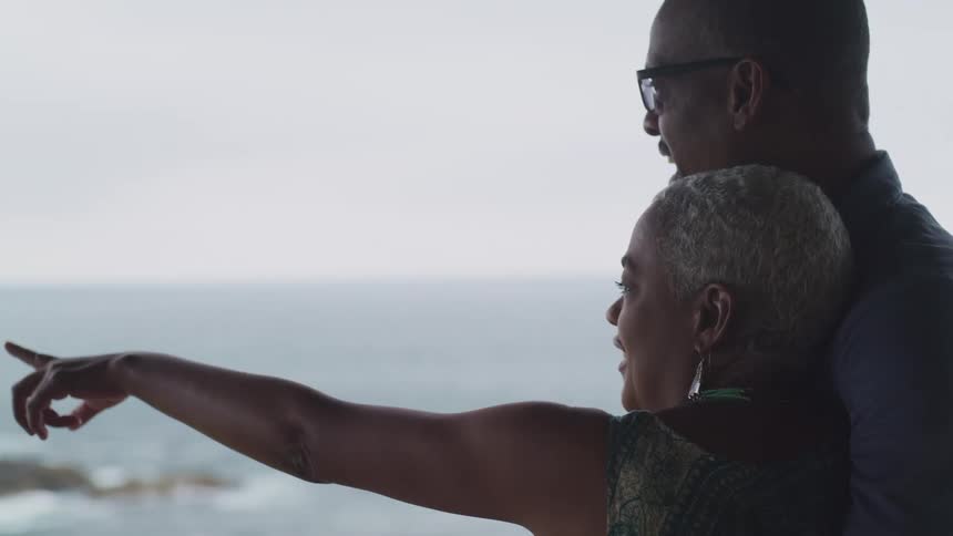 Couple hugs each other looking out over ocean