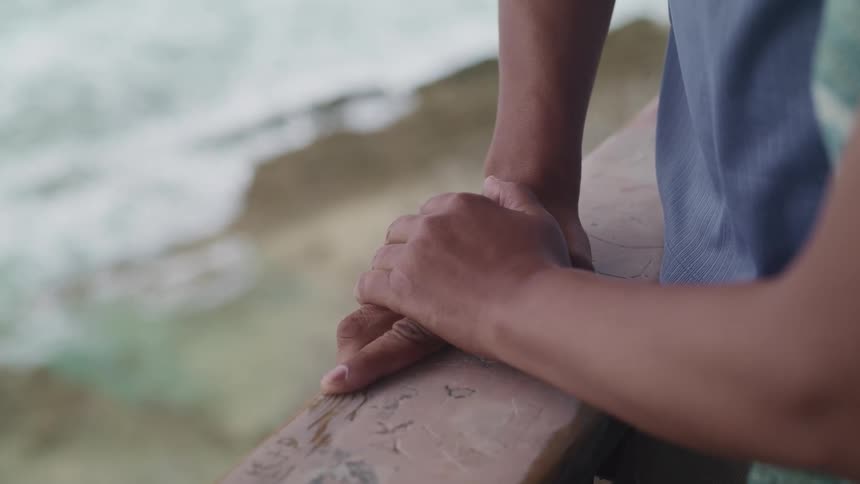 A woman leans against a railing and looks out at the water