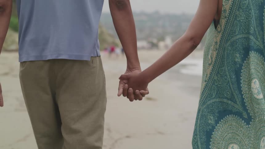 Couple walks along beach holding hands