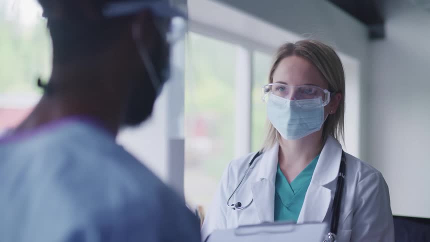 A medical professional speaks with a patient in a face mask