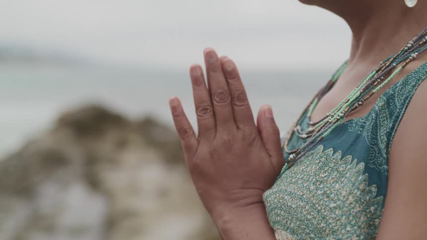 A woman standing on the shore prays