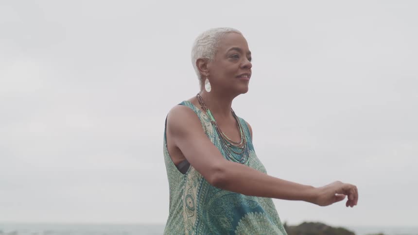 A woman is standing outdoors by the ocean