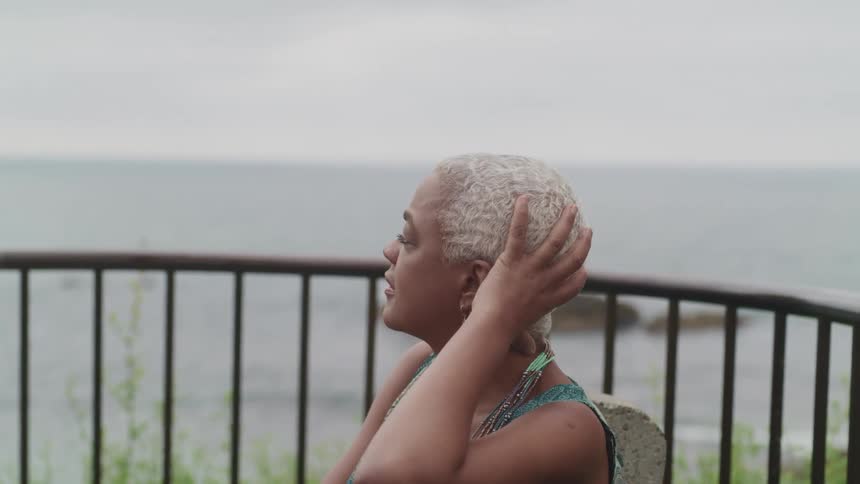 A woman is sitting outdoors near the coast