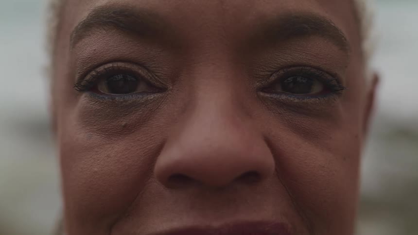 Black woman with grey short hair stares at the camera
