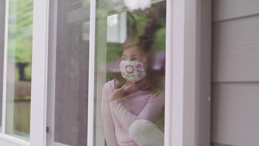 A child leans against the window inside looking out