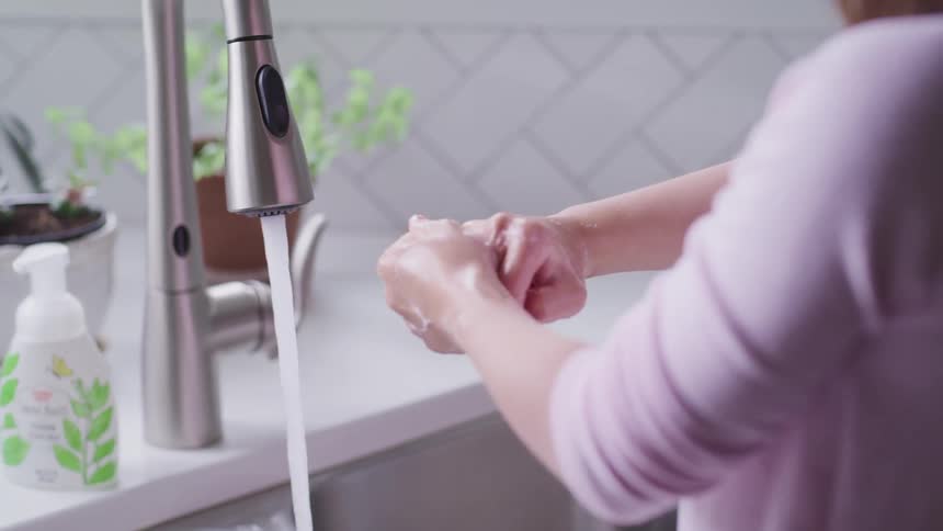 A woman is washing her hands in the kitchen