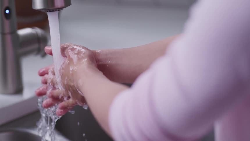 A woman is washing her hands in a sink