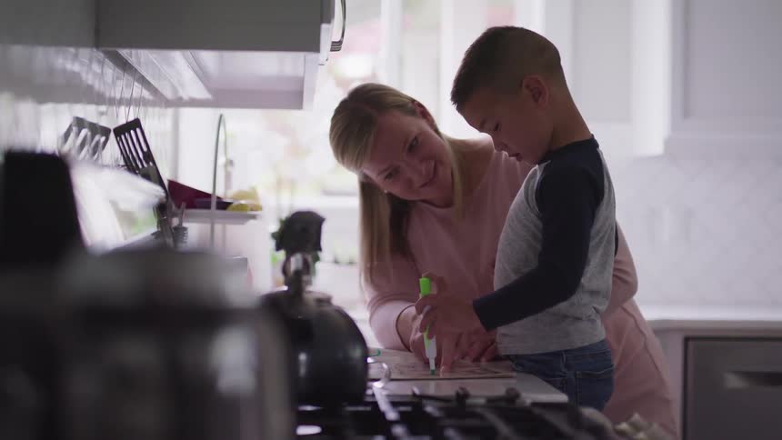 A mother is watching her son draw