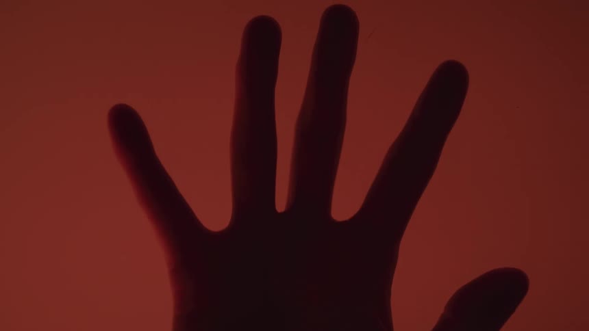A hand reaches up in the dark