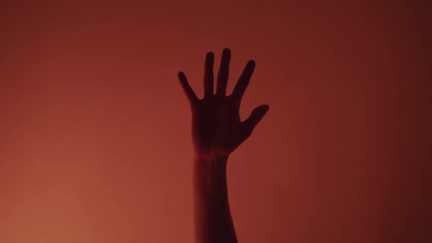 A person raising their hand with a red background