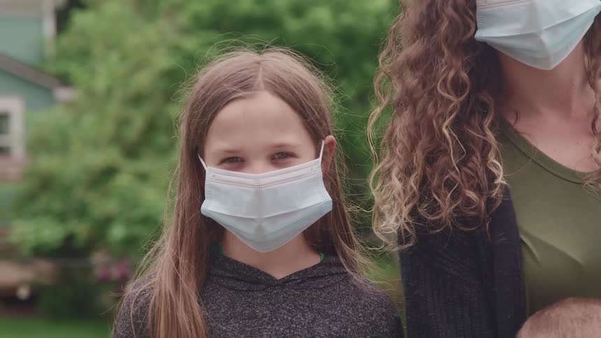 Daughter sitting next to her mother posing for a picture wearing a facial mask